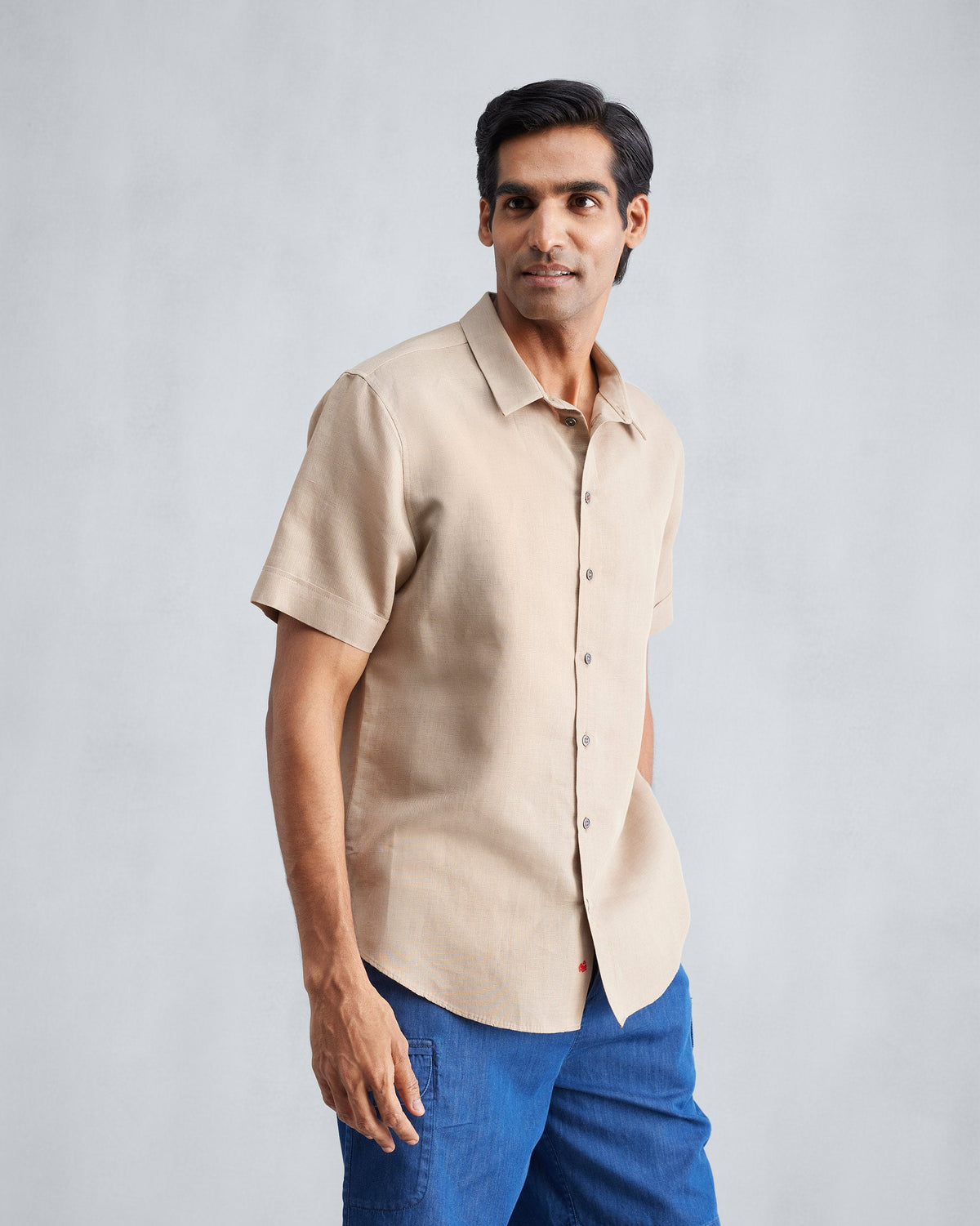 Person wearing a beige half sleeve shirt at a three-quarter angle.