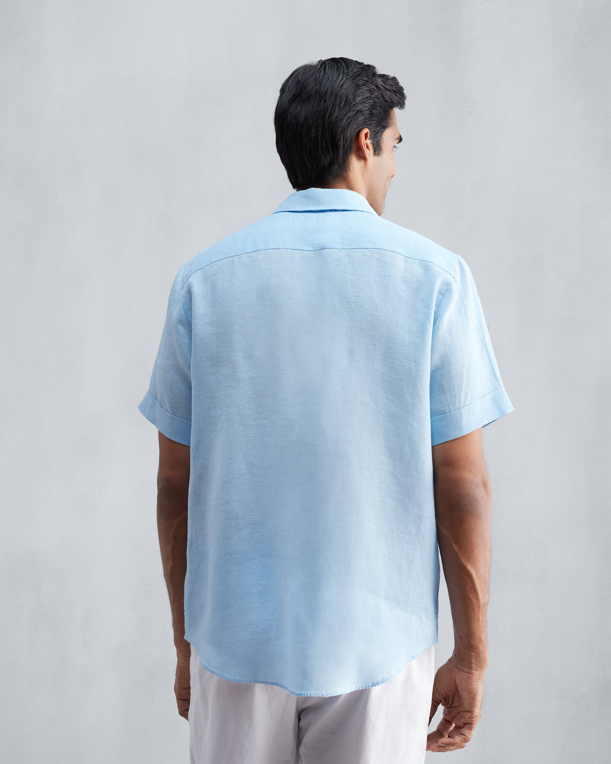 Back of a light blue half-sleeve shirt with a yoke seam.