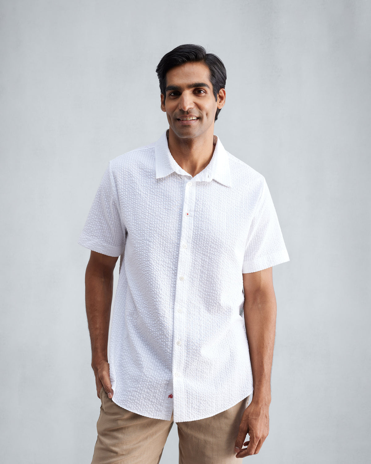 Person wearing a white half-sleeve seersucker shirt with a pointed collar.