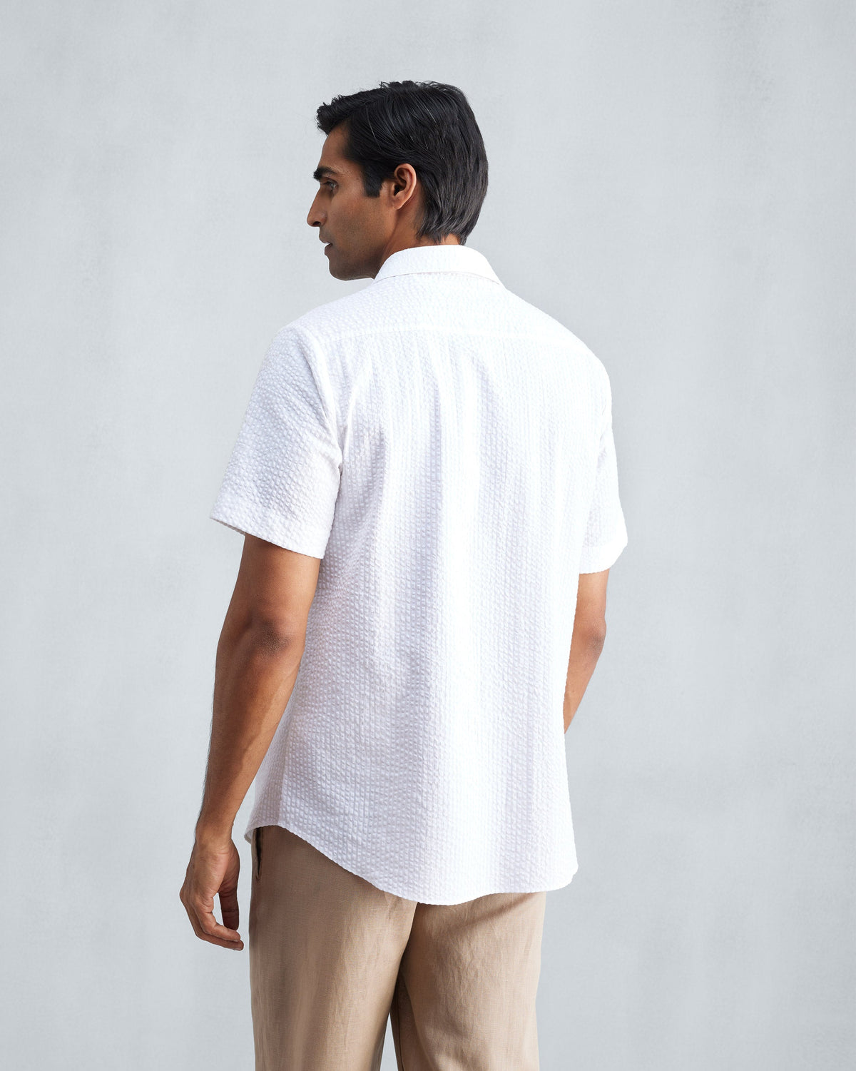 Back of a white seersucker half sleeve shirt worn by a person.