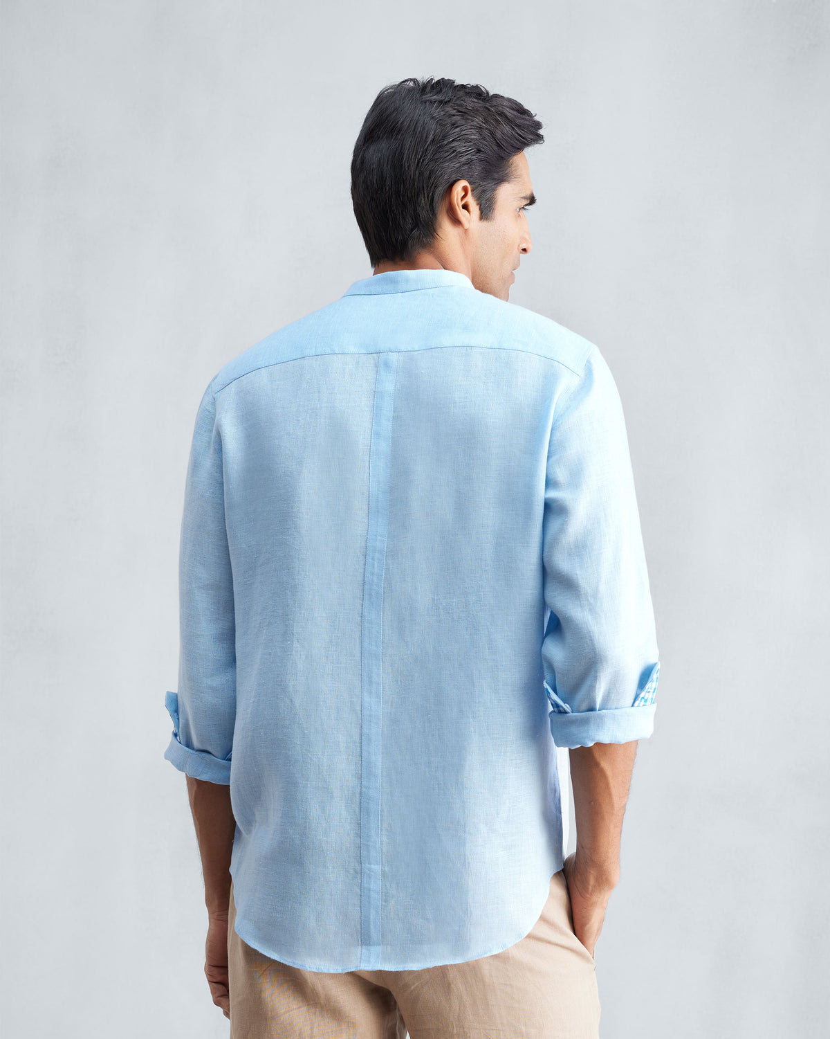Back of a light blue Nawab shirt with a center back seam and rolled sleeves.