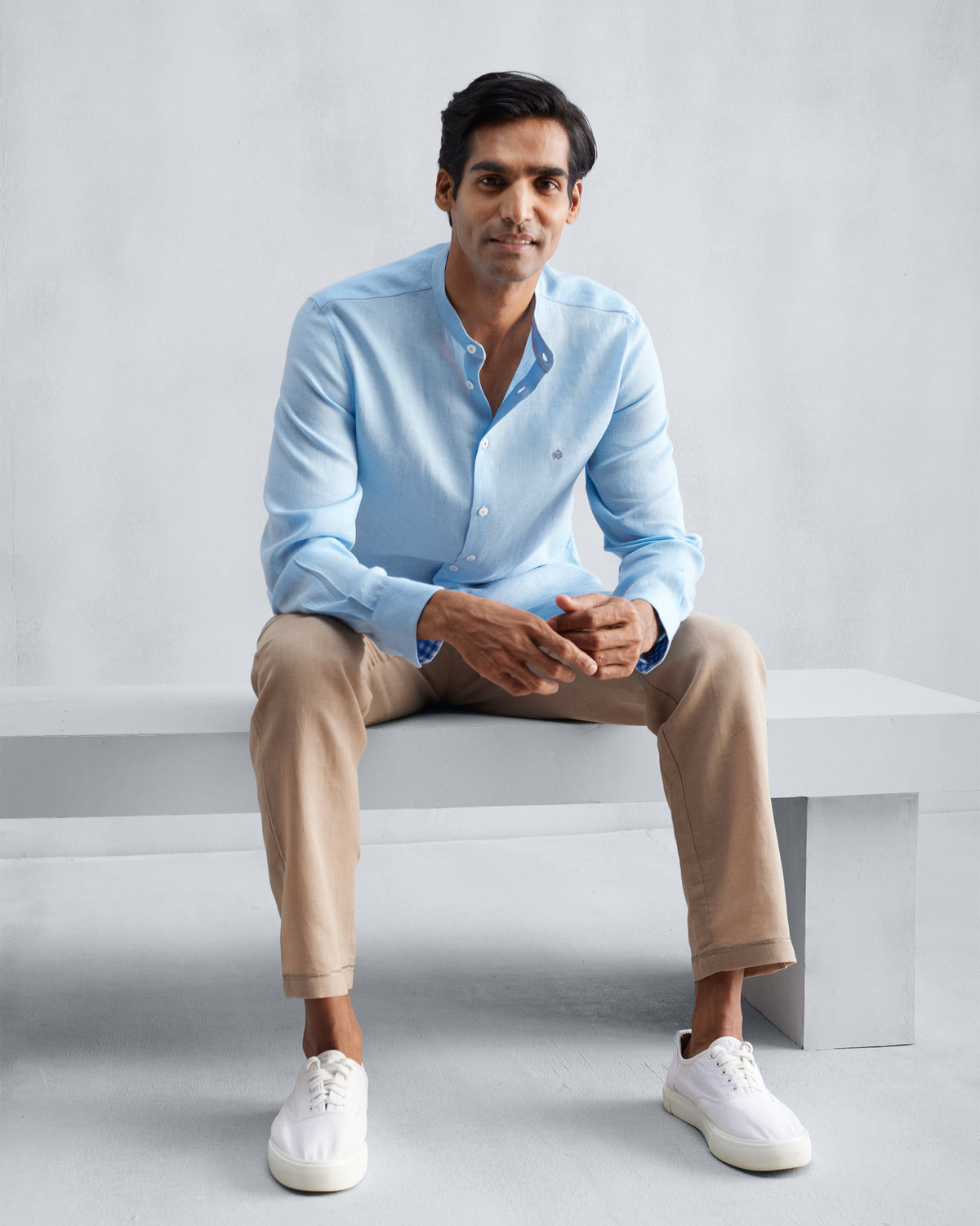 Person wearing a light blue Nehru collar Nawab shirt with tan trousers.