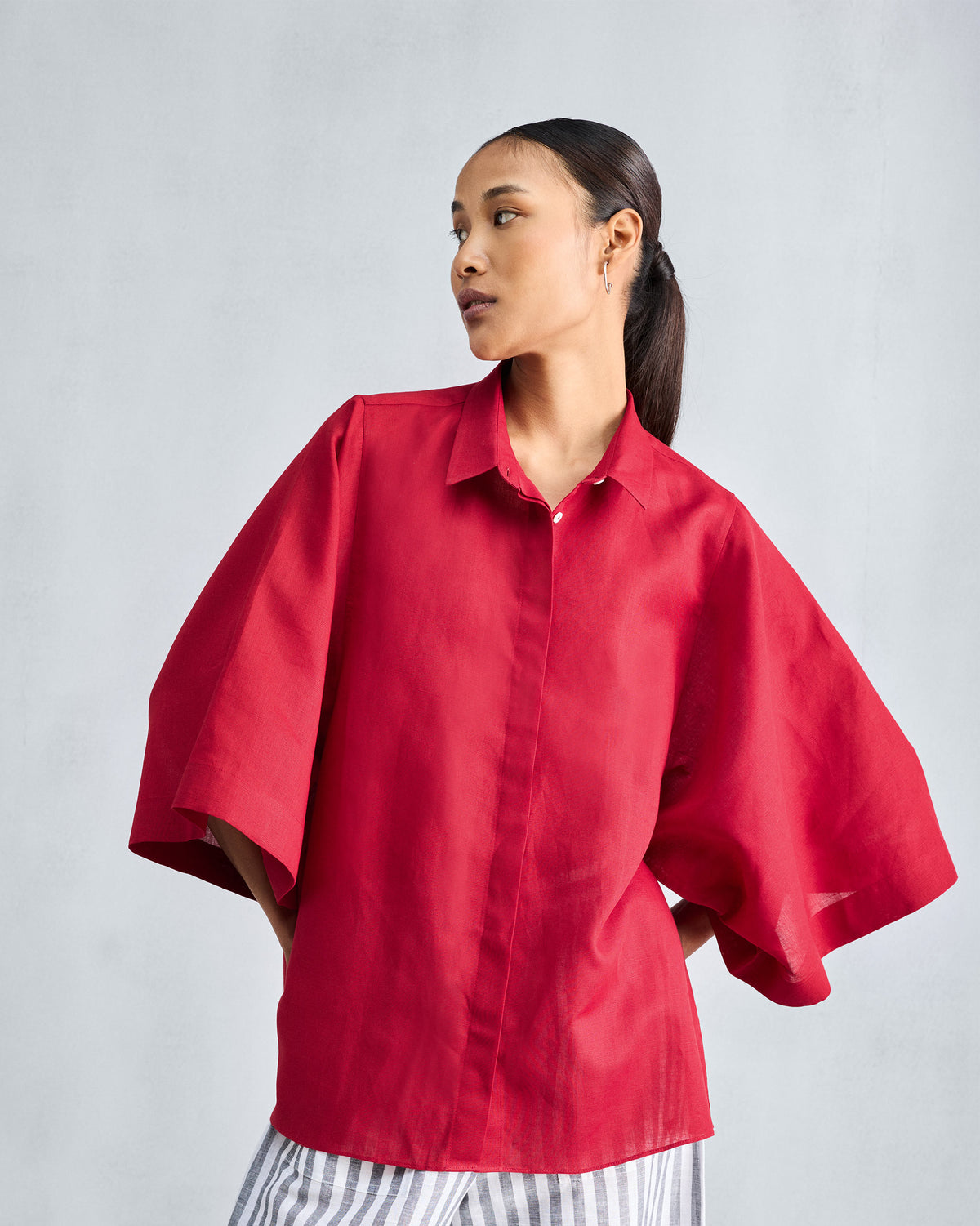 Person wearing a red drop armhole shirt with wide sleeves.