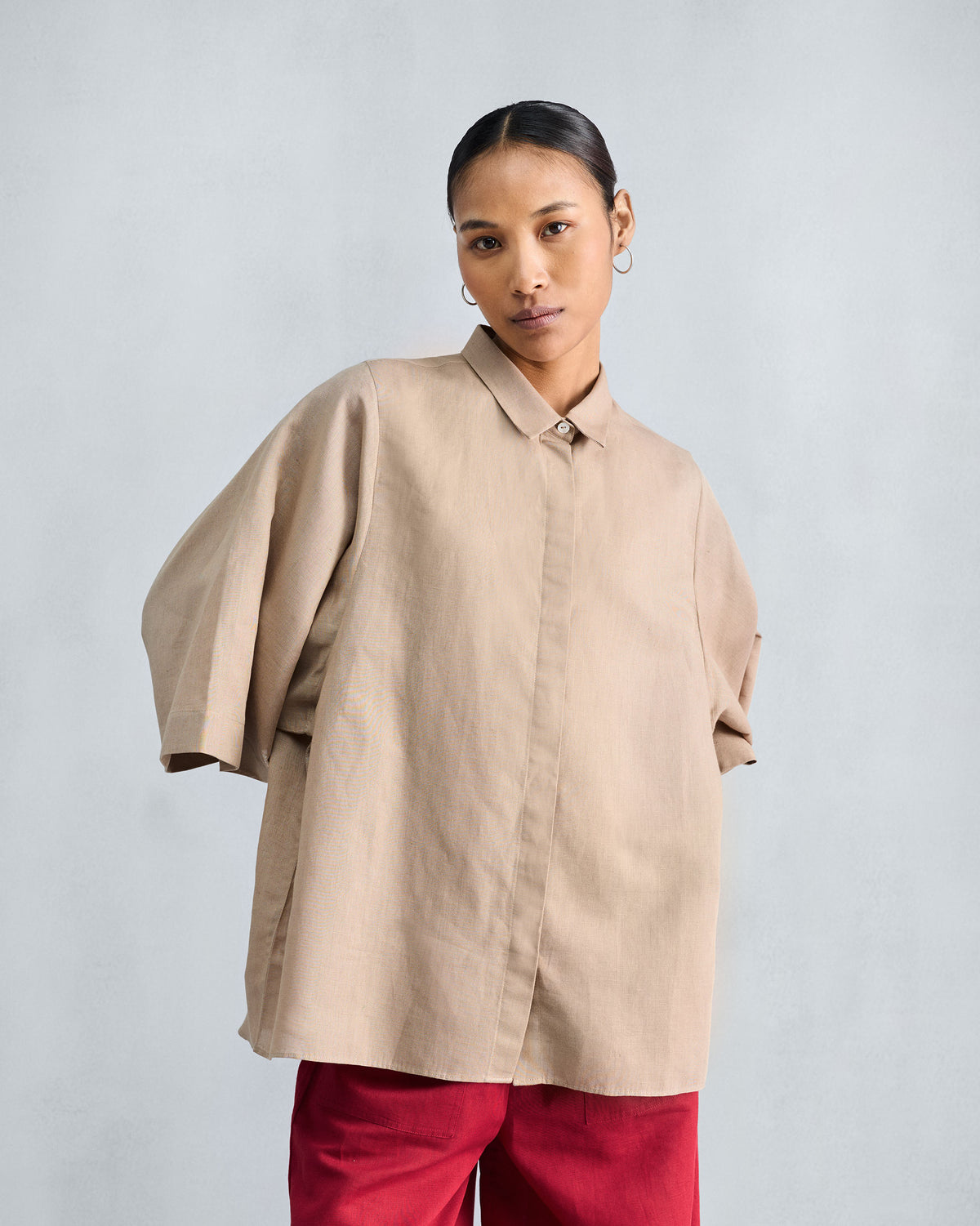 Beige drop armhole shirt with a pointed collar and a hidden button placket.