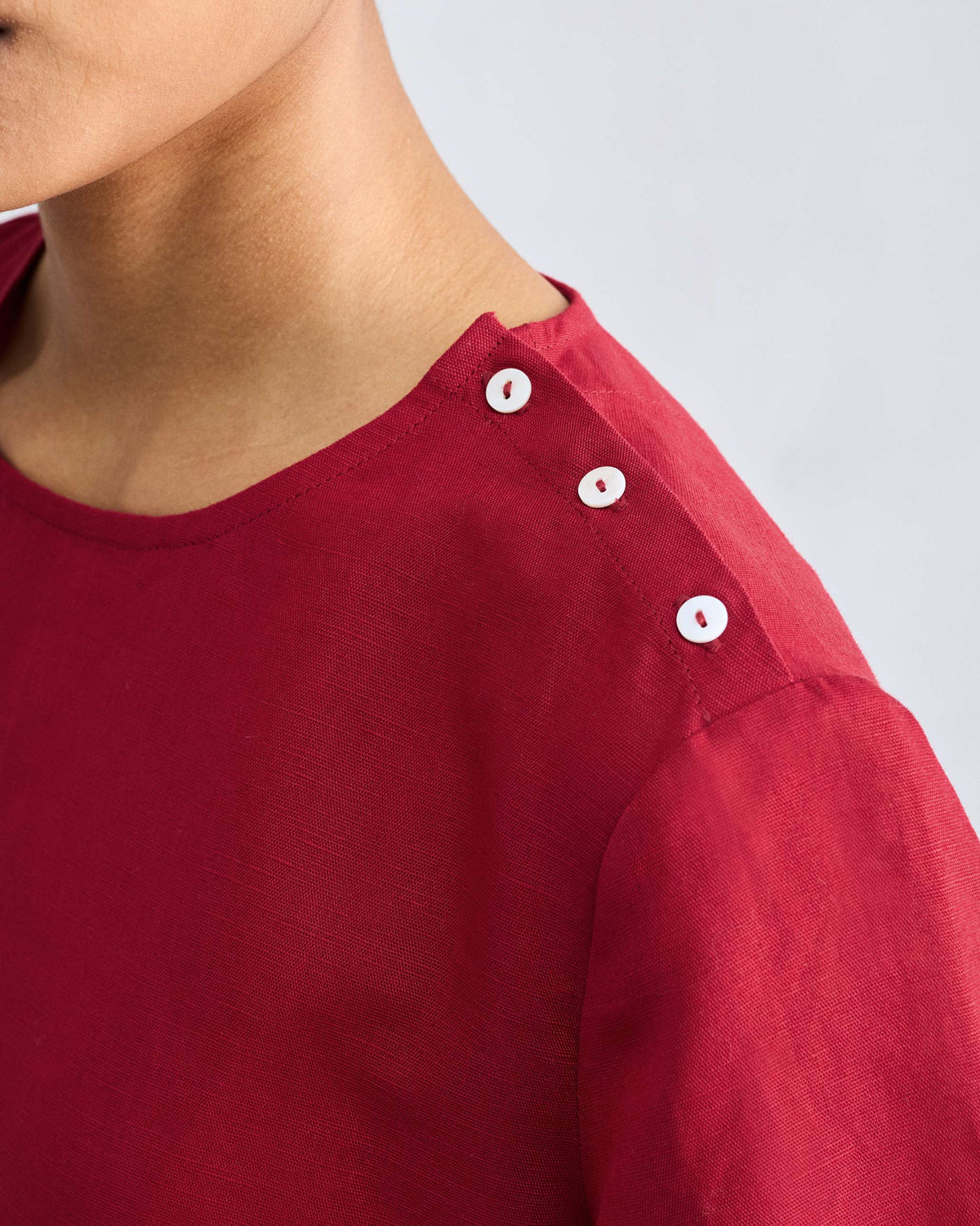 Close-up of a red High Slit Top showing white buttons on the shoulder.