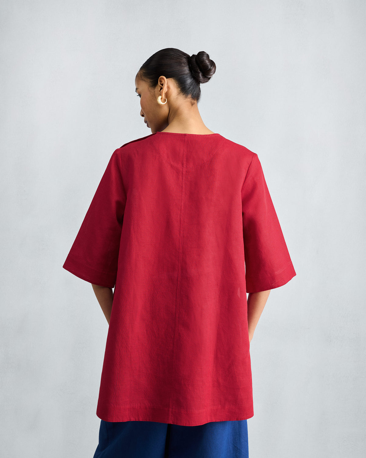 Back of a red High Slit Top with a center seam and elbow sleeves.
