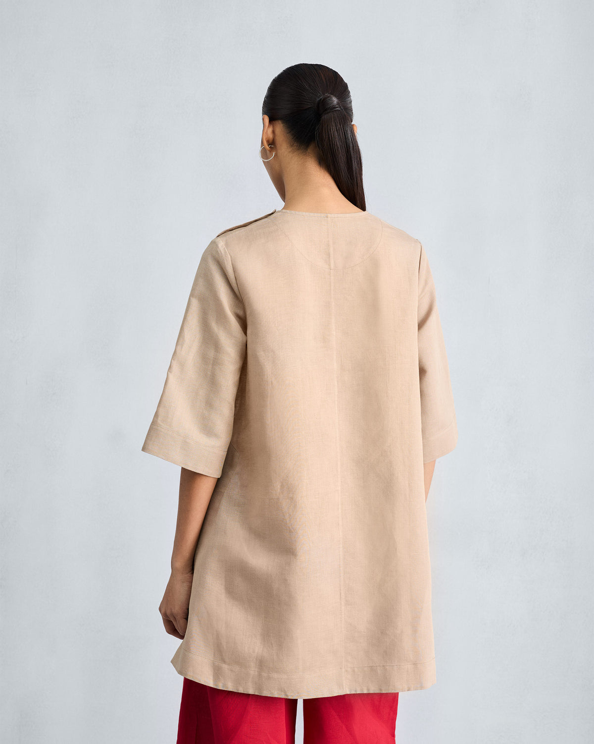 Back of a beige High Slit Top with a center seam and elbow sleeves.