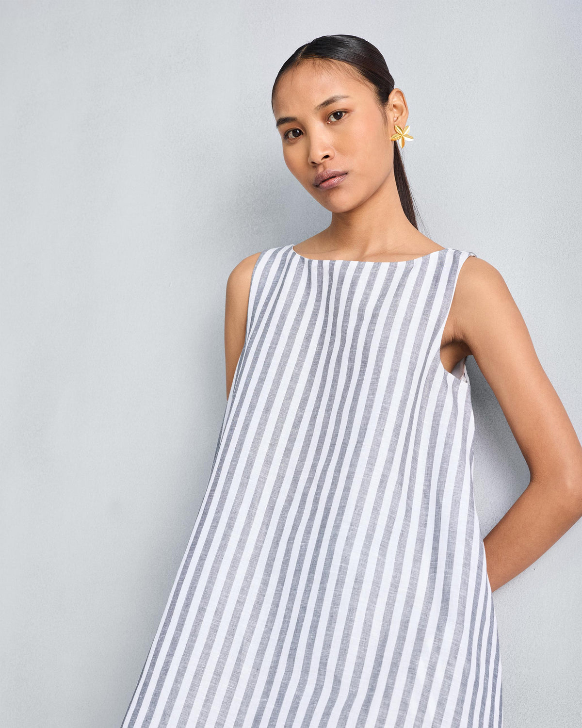 Person wearing a charcoal and white striped double-layer dress with a boat neck.