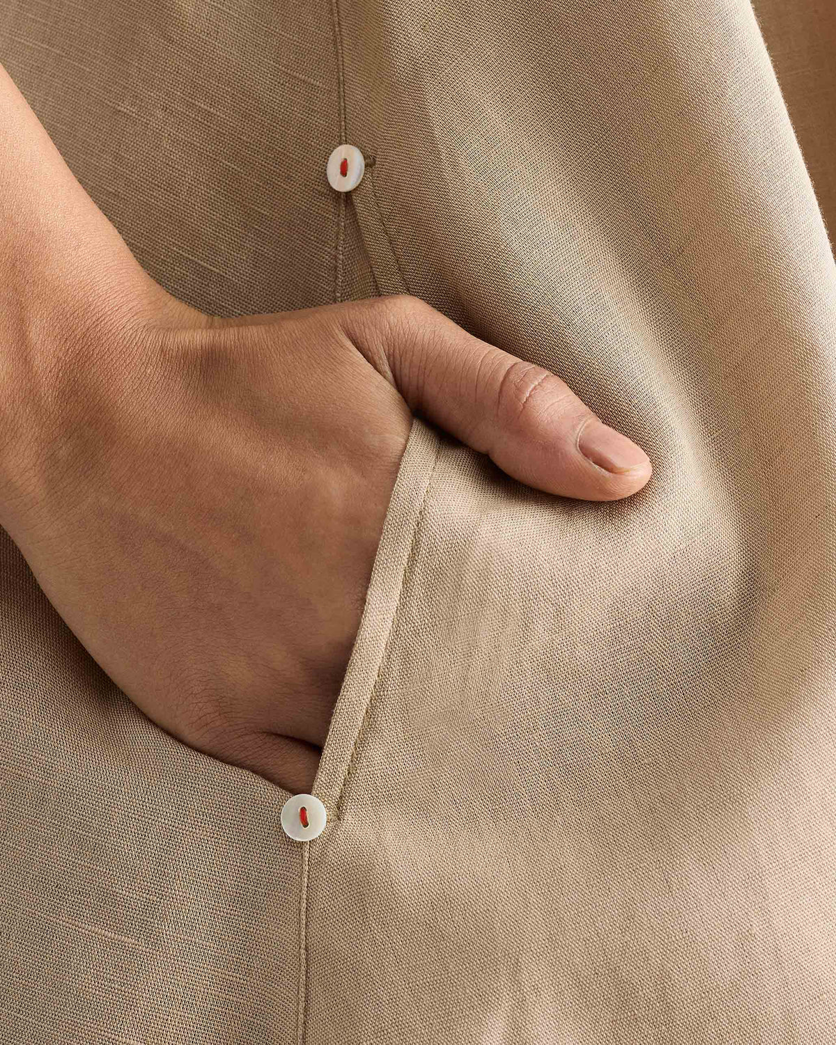 Close-up of a beige Double Layer Dress side pocket with white buttons.