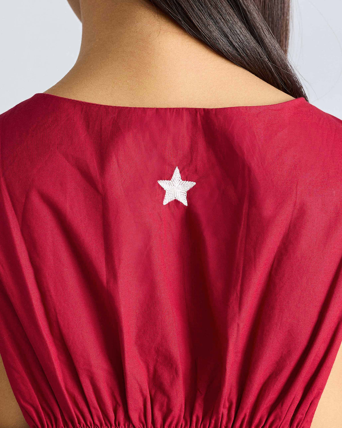 Close-up of the back of a red Short Racerback Dress showing a white star embroidery.
