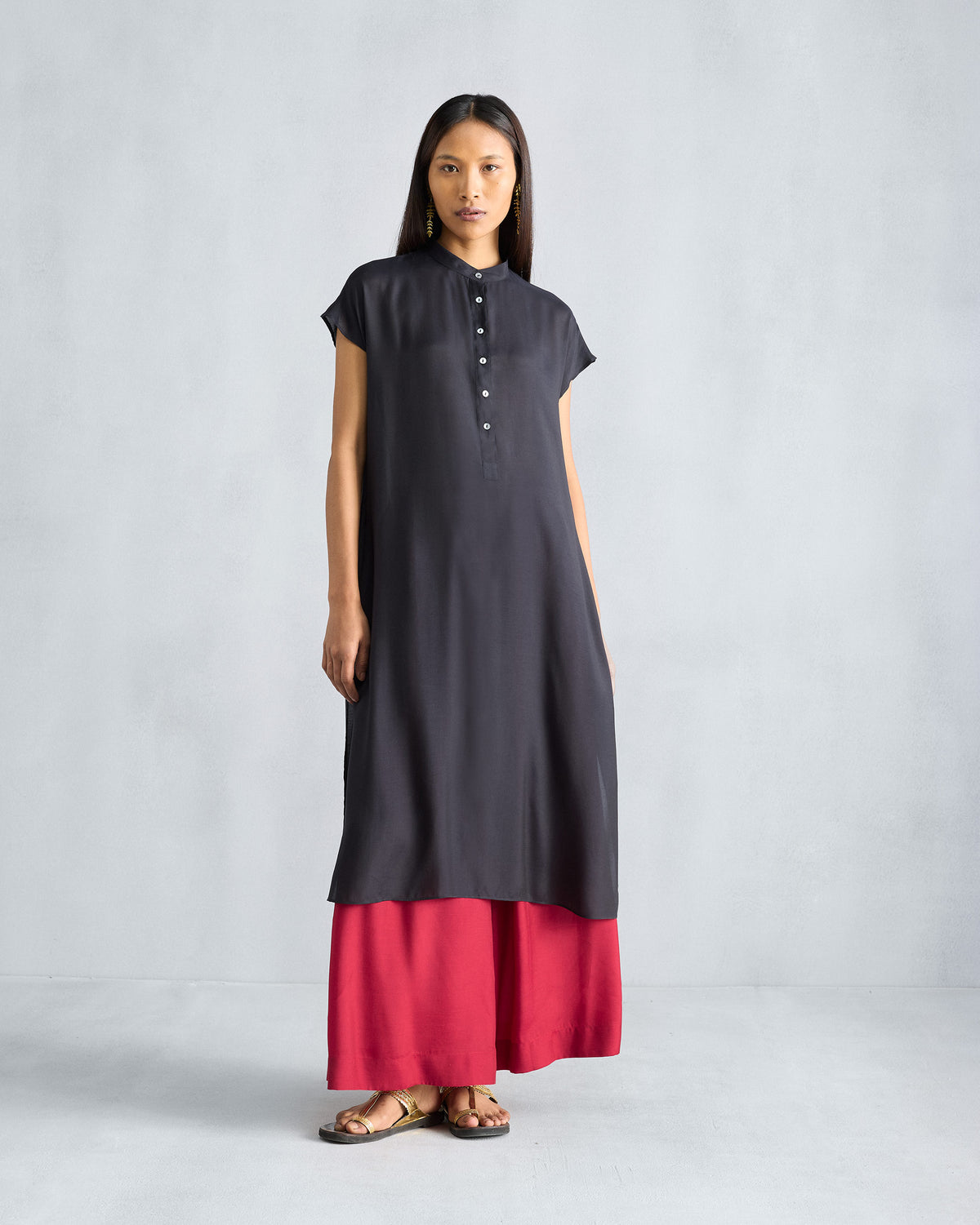Person wearing red Classic Pyjama pants under a long black tunic.