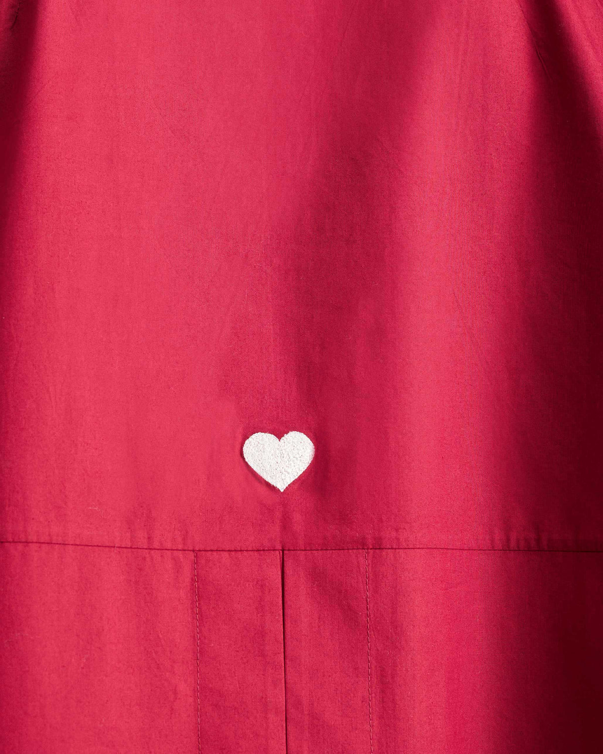Close-up of a white heart embroidered on a red Cirrus shirt.