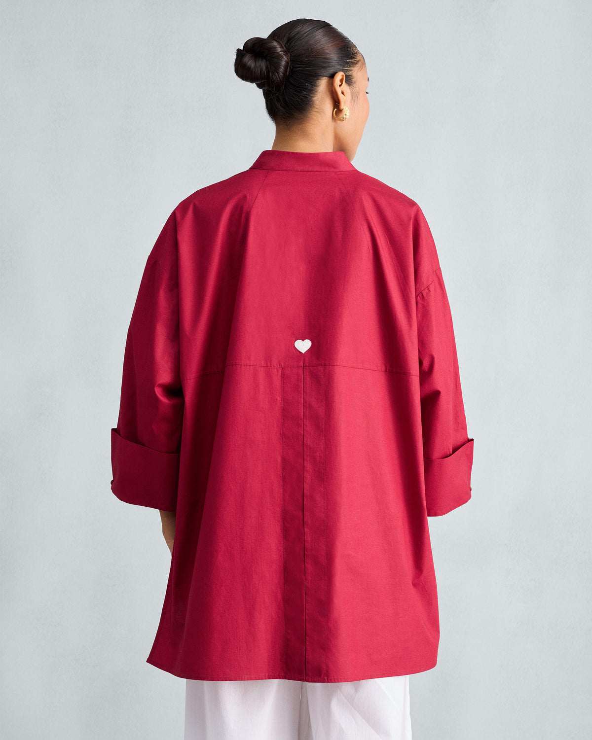 Back of a red Cirrus shirt with a white heart at the yoke and wide folded cuffs.