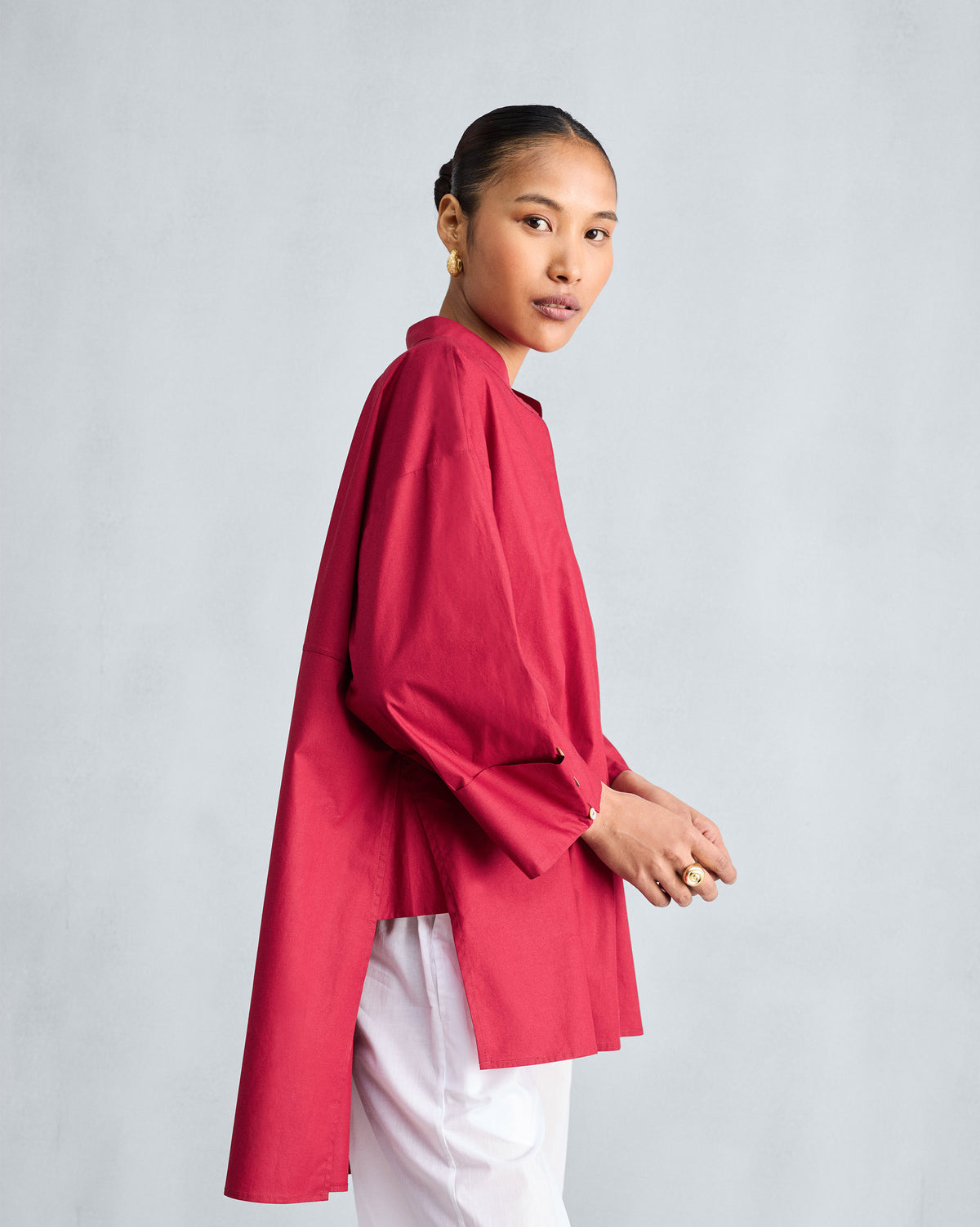 Side view of a red Cirrus shirt showing the high-low hem and deep side slit.