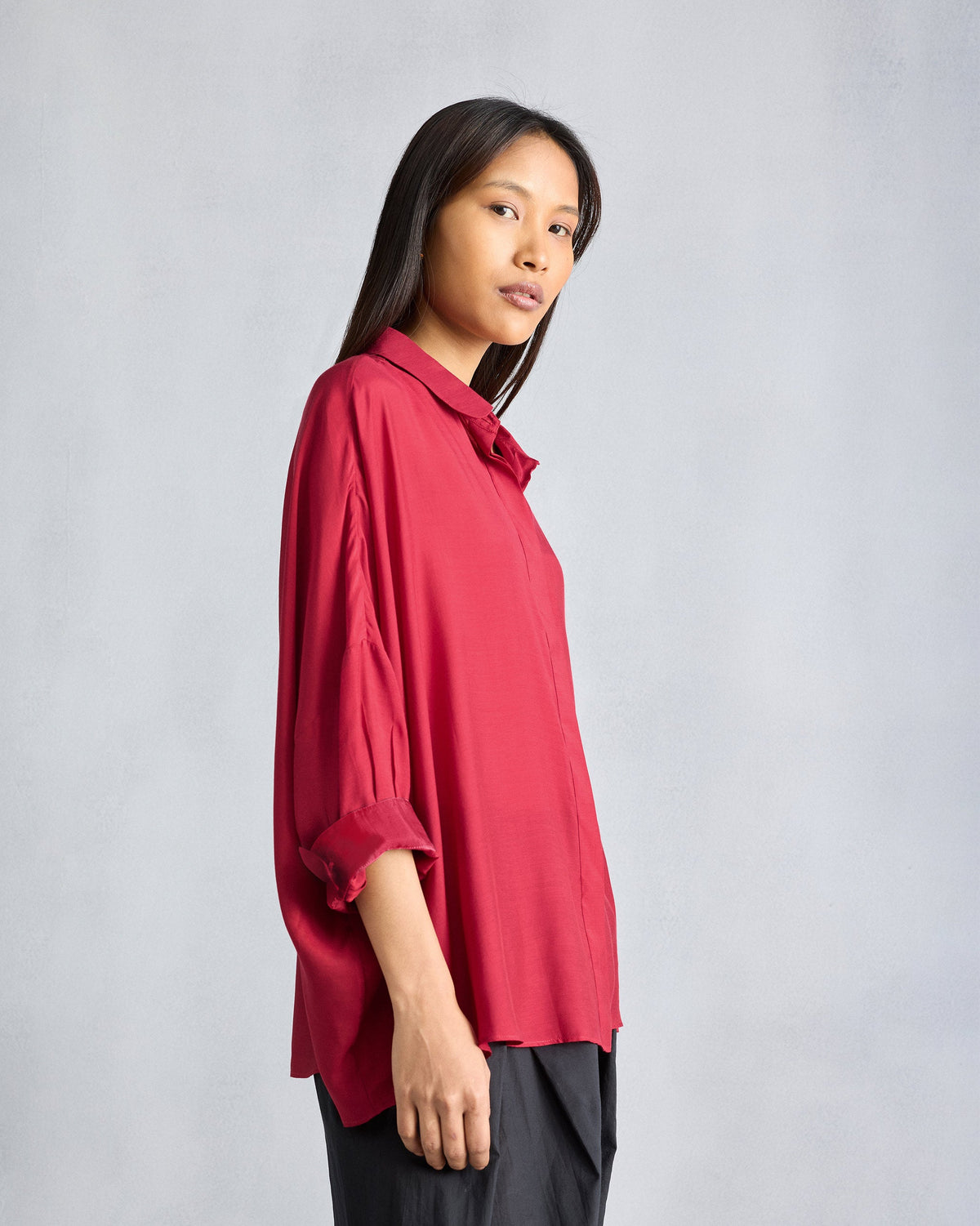 Side view of a red Boxy shirt with an oversized drape.