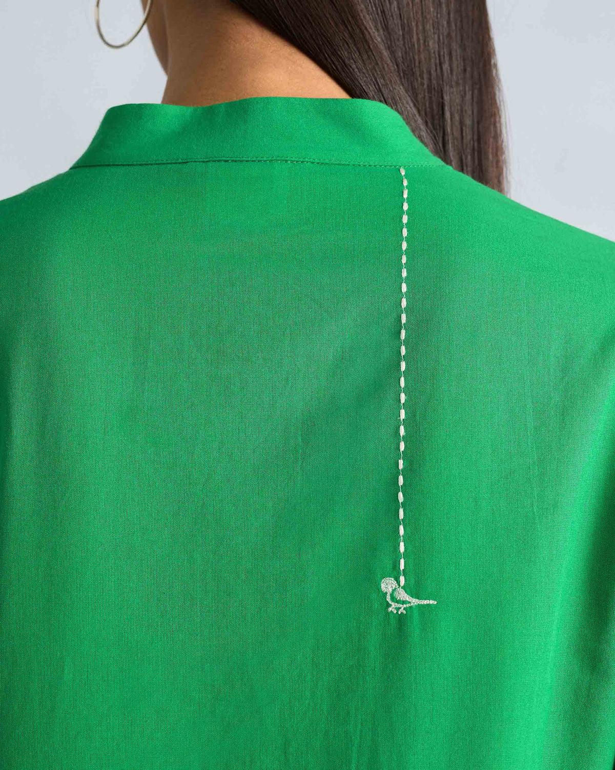Close-up of white bird embroidery on the back of a green kurta.