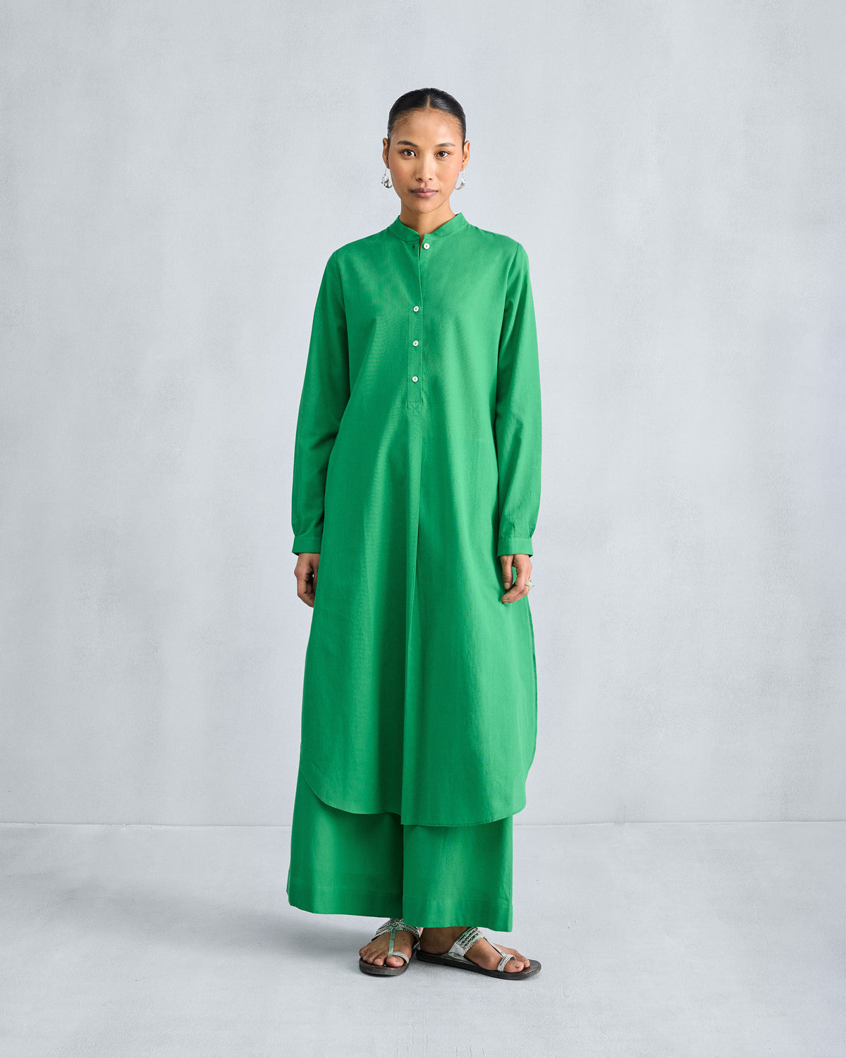 Green long kurta and matching trousers showing the curved shirt-tail hem.
