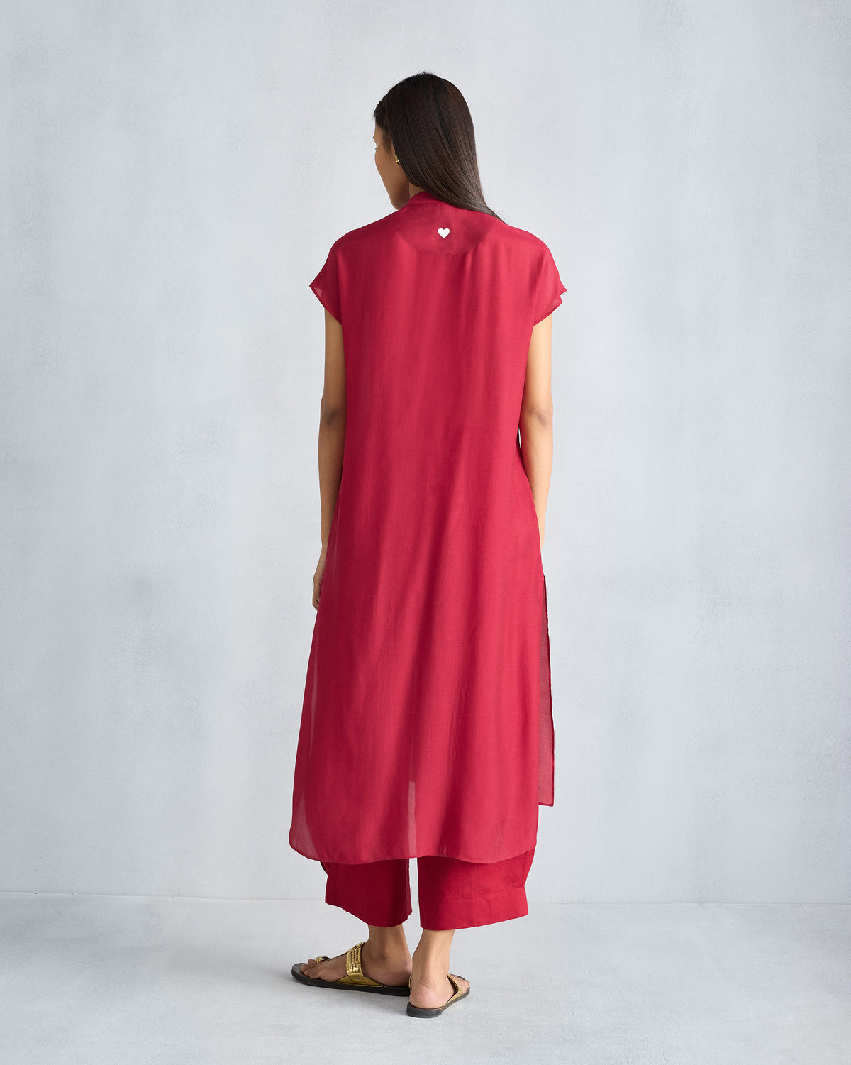 Back of a red short sleeve kurta with a white heart below the neckline.