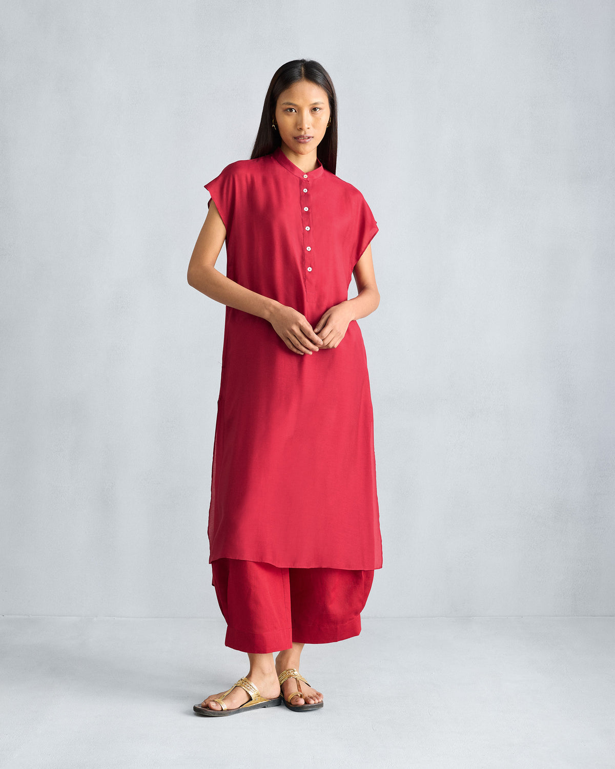 Person wearing a red short sleeve kurta with matching red trousers.
