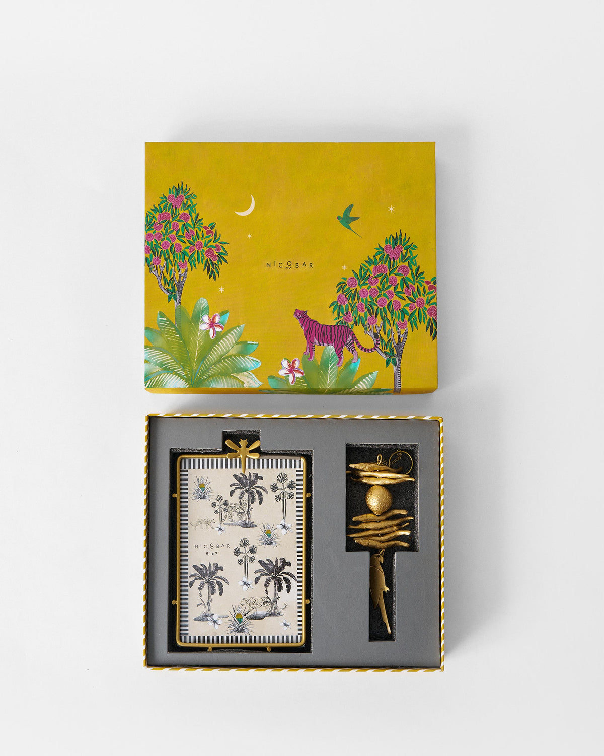 Open Madagascar gift box with a dragonfly frame insert and a gold hanging charm.