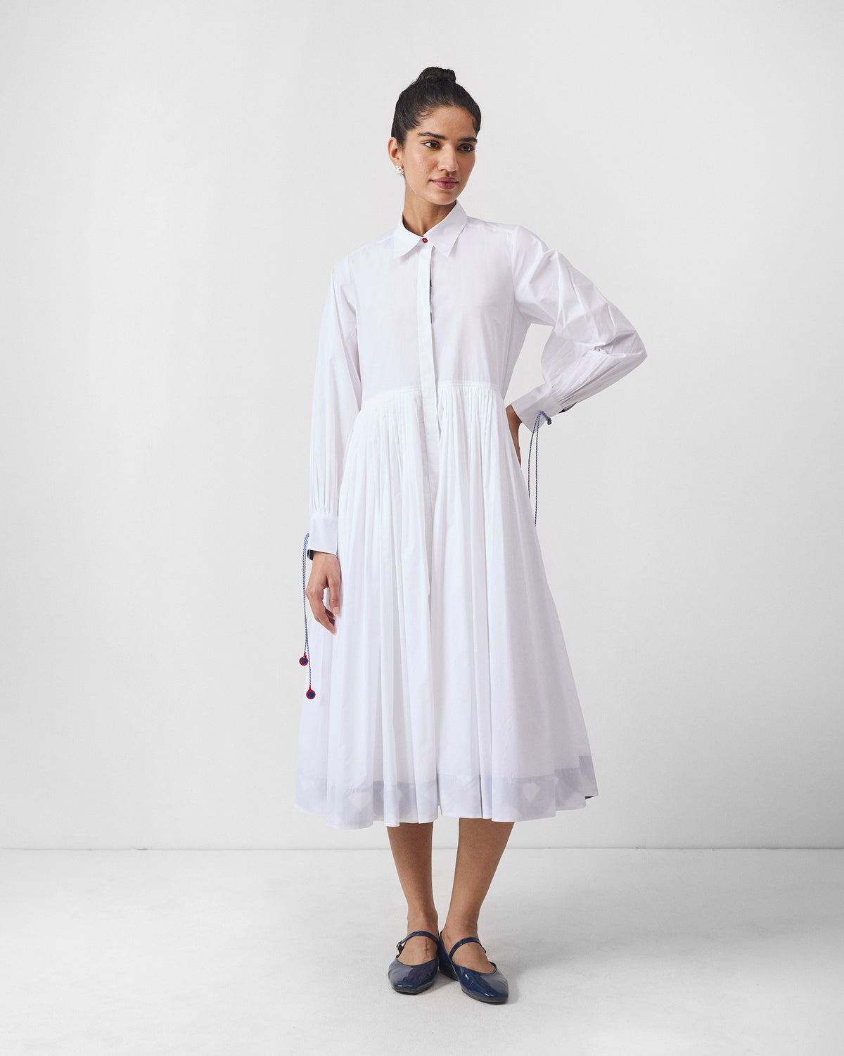 White Puritsu shirt dress with a pleated skirt and cutwork hem border.