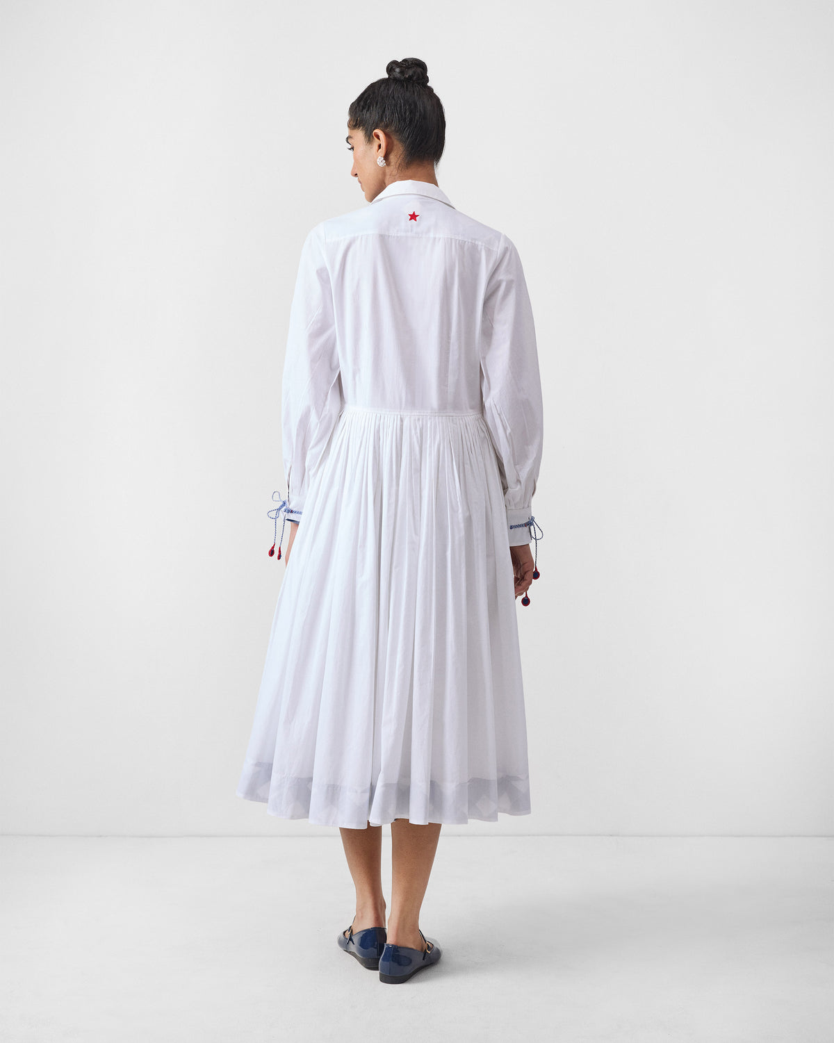 Back of a white Puritsu shirt dress with a red embroidered star.