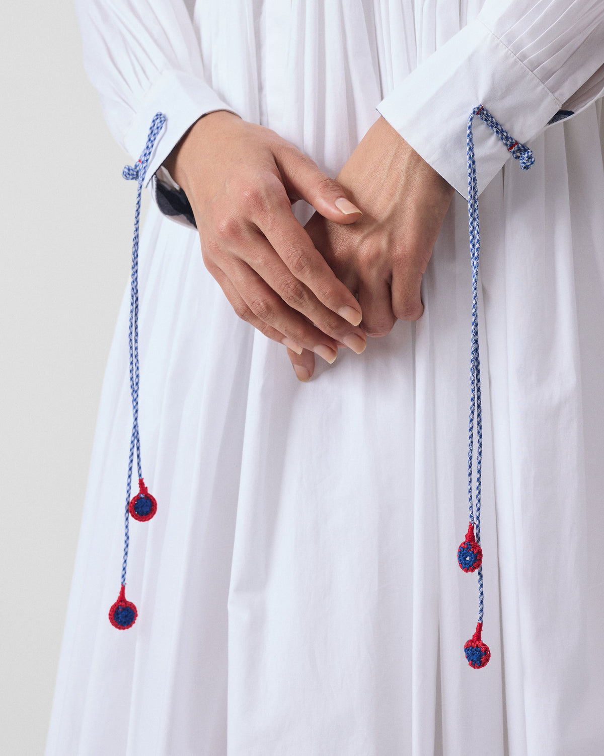 Close-up of gingham cuff cords on the white Puritsu shirt dress.