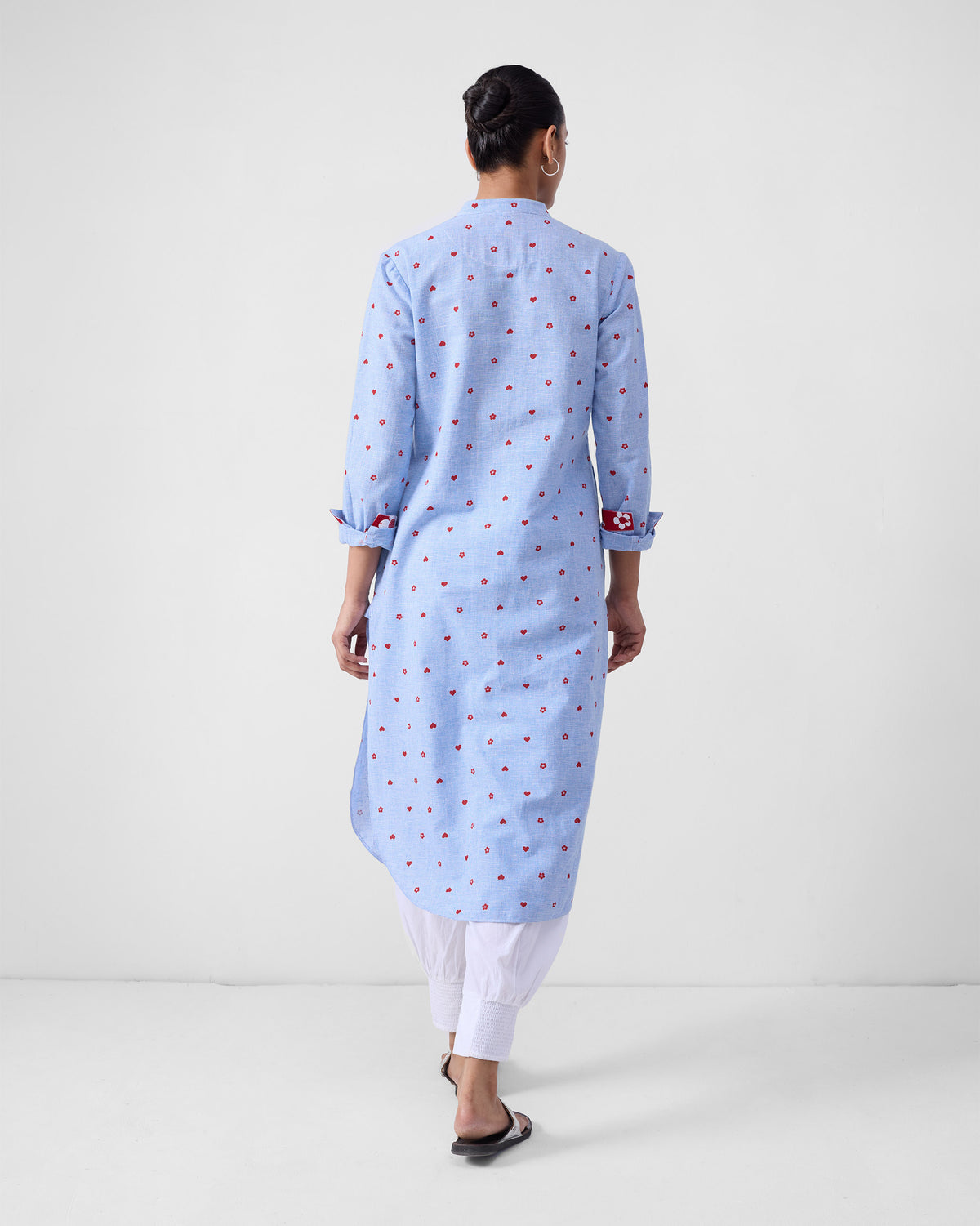 Back of a blue check kurta with red motifs and rolled cuffs with red lining.