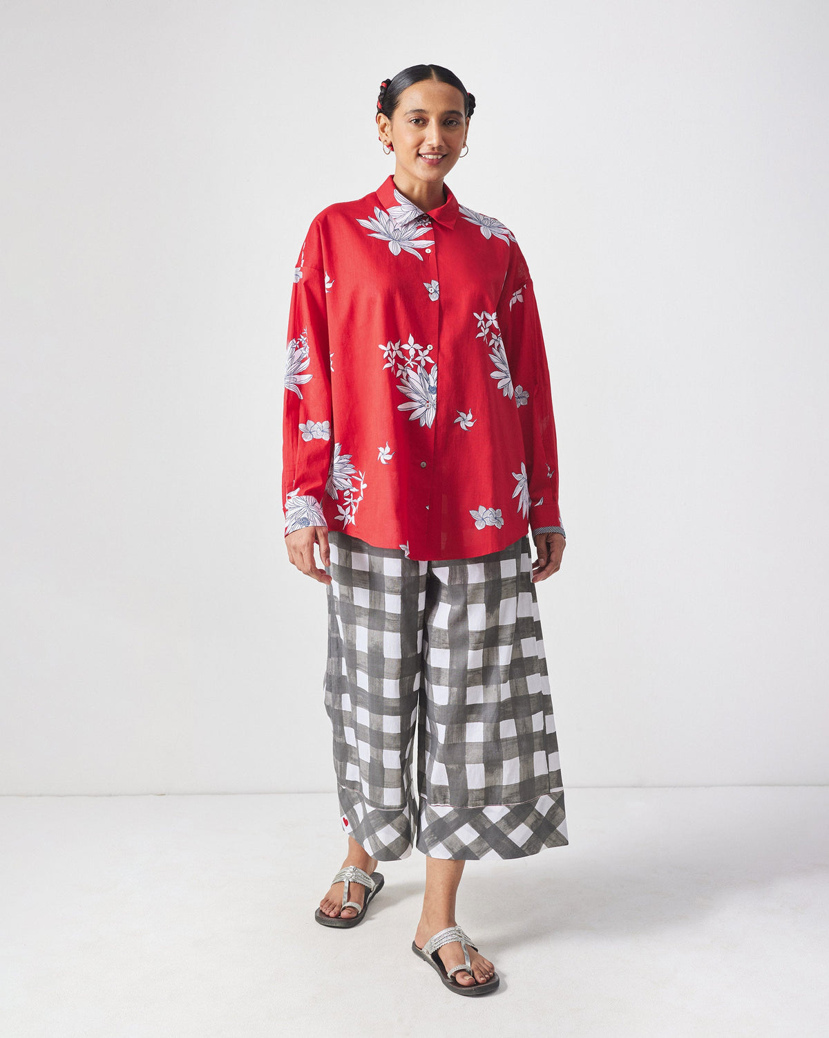 Person wearing a red floral oversized shirt and grey check trousers.