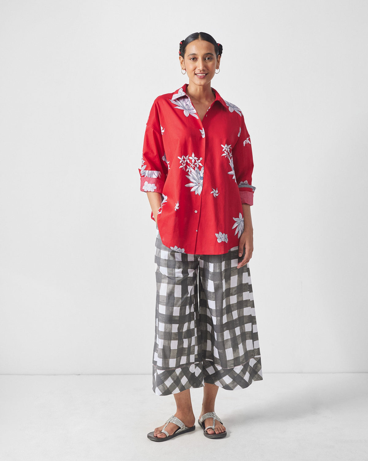 Full view of a red floral oversized shirt worn with grey gingham trousers.