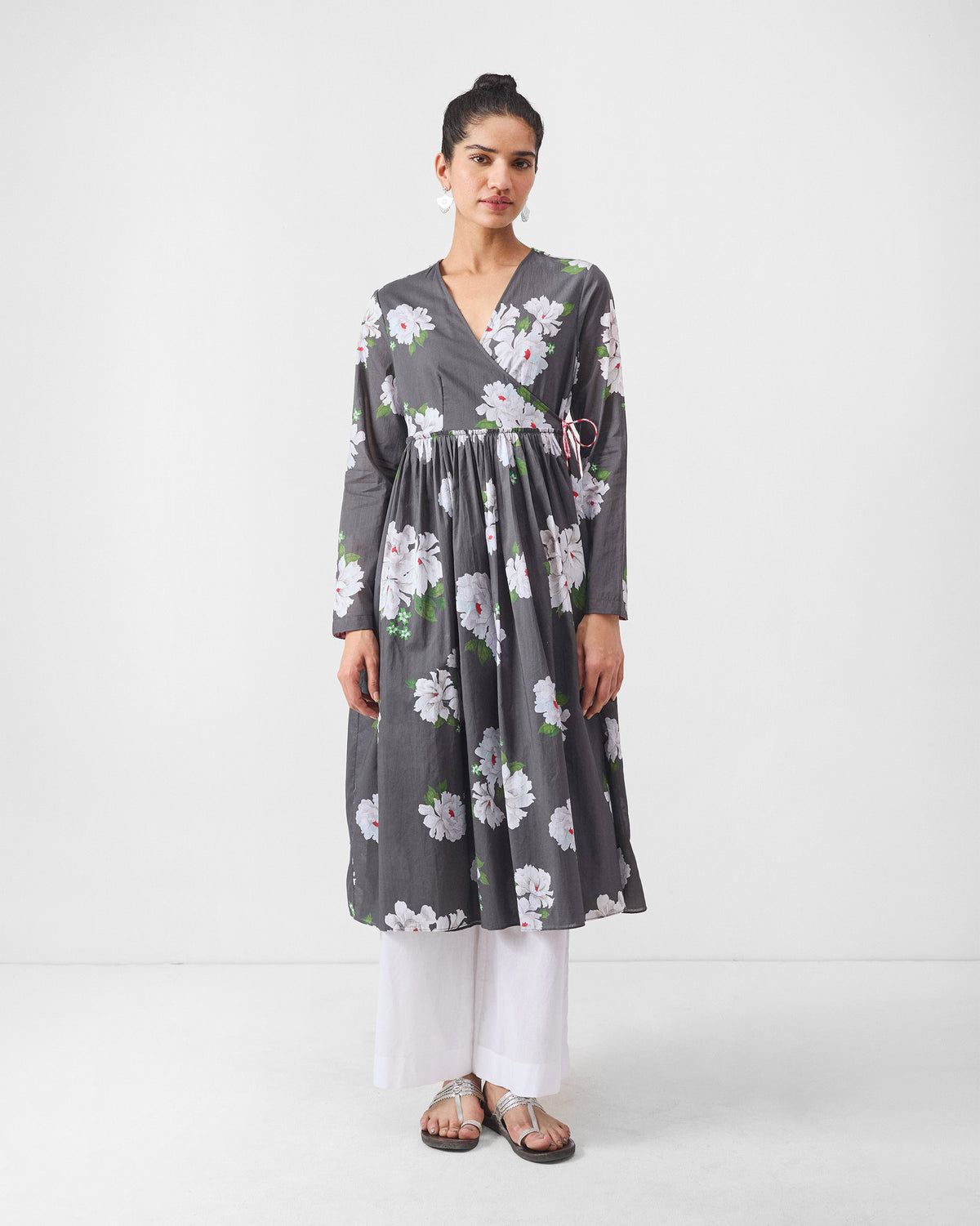 Person wearing a charcoal wrap angrakha with ivory flowers.