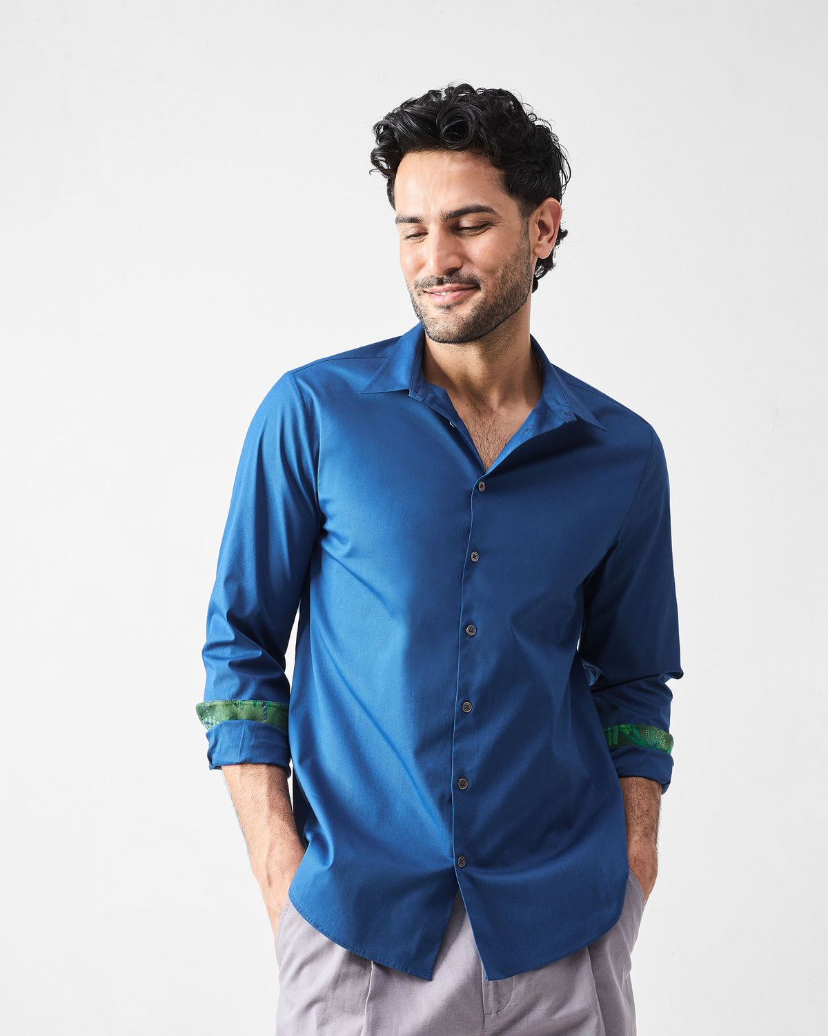 Person wearing a dark blue Hakuna Shirt with green leaf print cuff lining.
