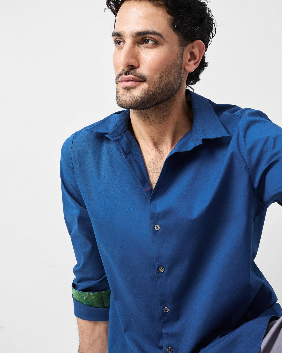 Person wearing a dark blue Hakuna Shirt with a pointed collar and green cuff lining.