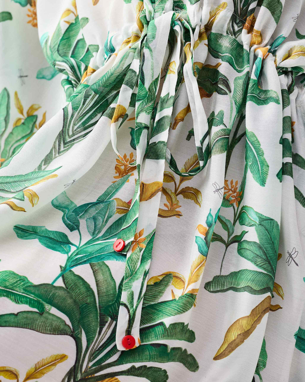 Close-up of green palm leaves on a white Munnar Kaftan.