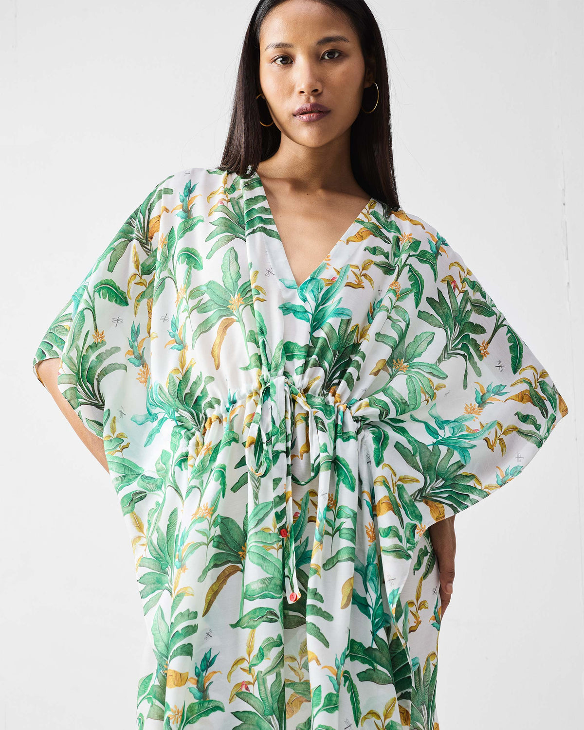 Person wearing a white Munnar Kaftan with a deep V-neck and drawstring waist.