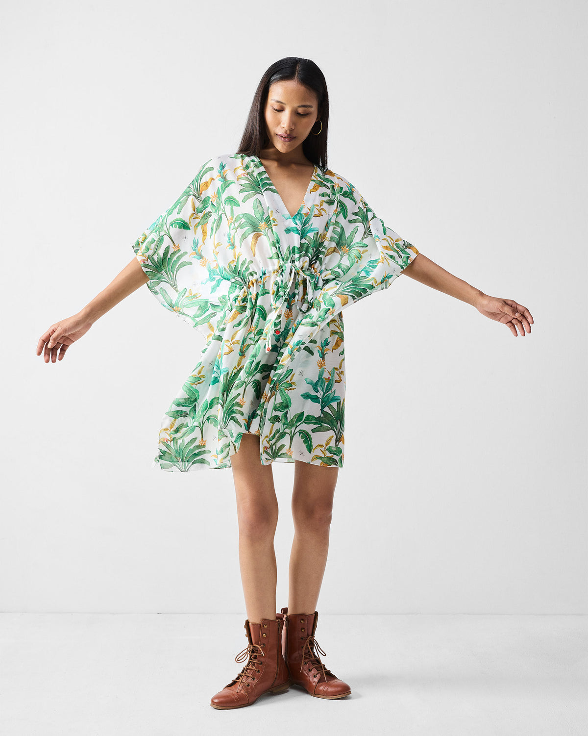 Person wearing a short white Munnar Kaftan with a green tropical print.