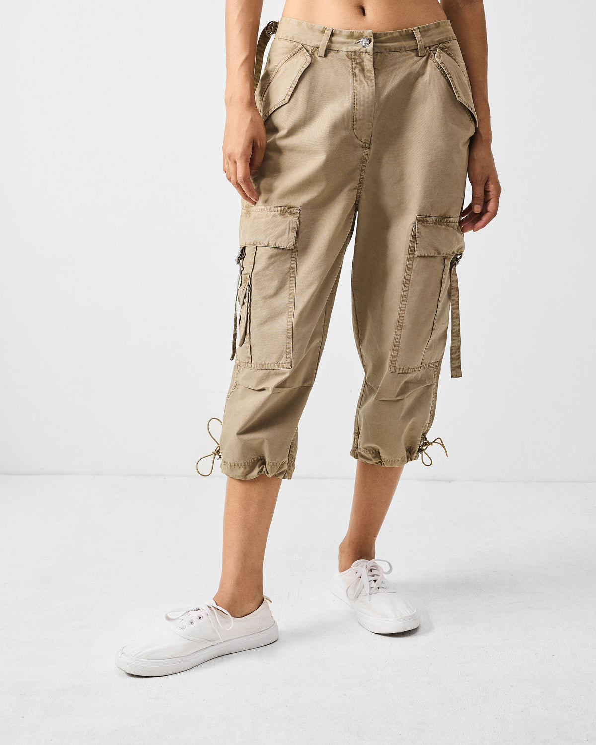 Person wearing khaki Vellore Capris with cargo pockets and drawstring hems.