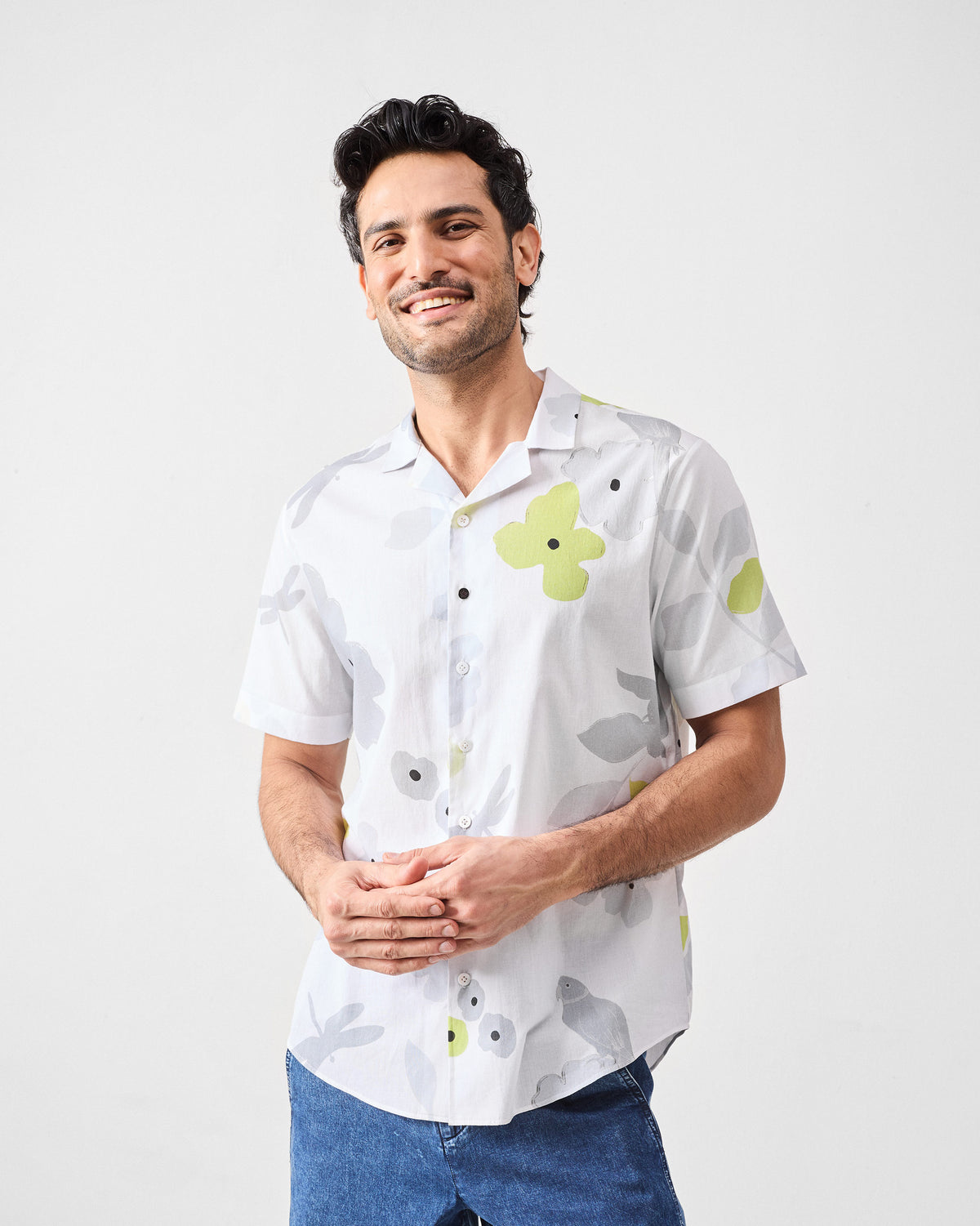 Person wearing a white Mistari Shirt with large lime and grey floral motifs.