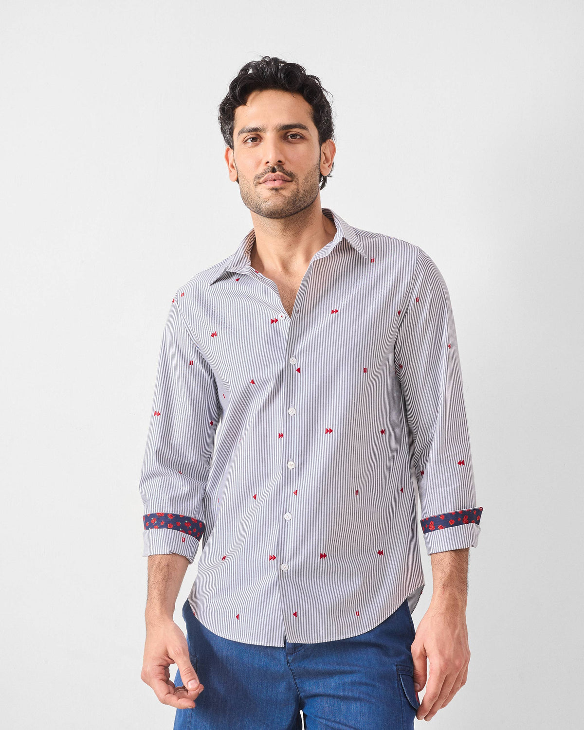 Person wearing a white pinstripe Hakuna Shirt with red embroidery and floral cuffs.