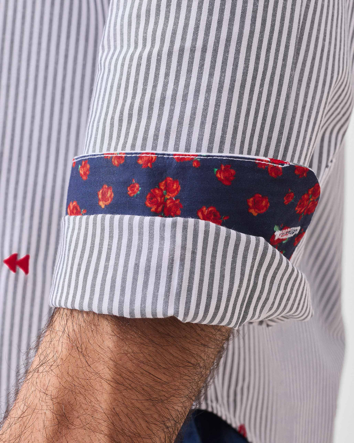 Close-up of a Hakuna Shirt cuff lining with red roses and pause embroidery.