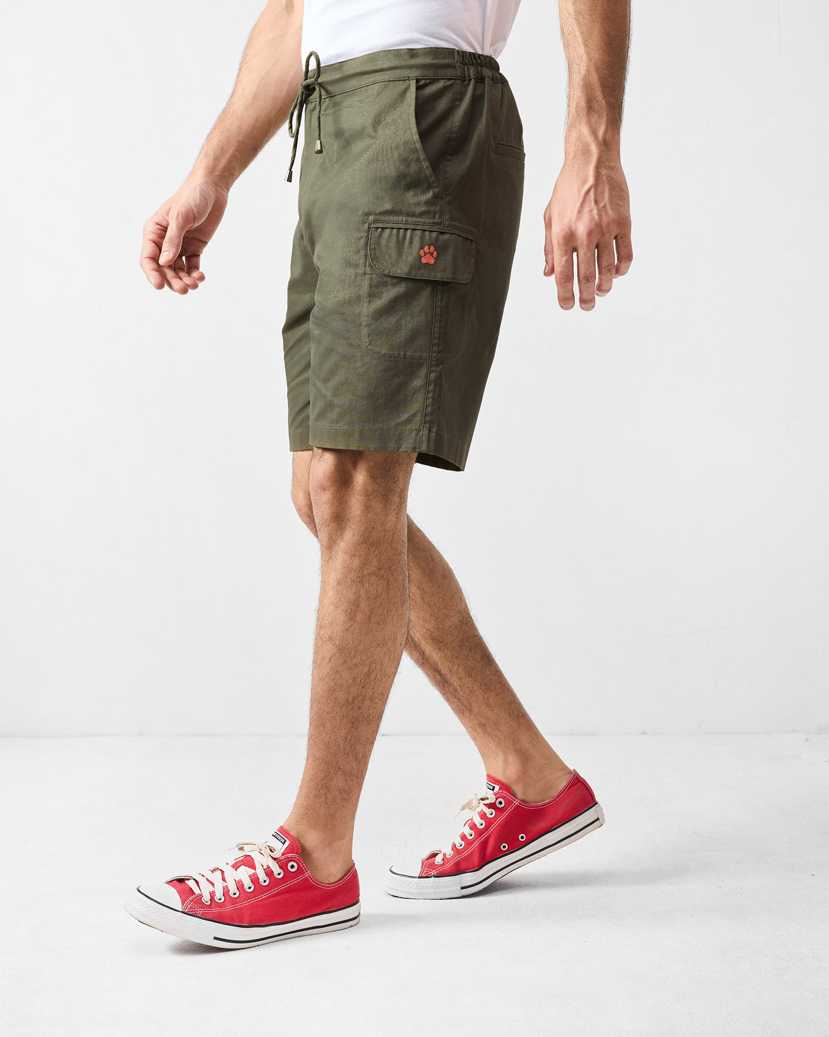 Side view of olive utility shorts showing a cargo pocket with a paw motif.