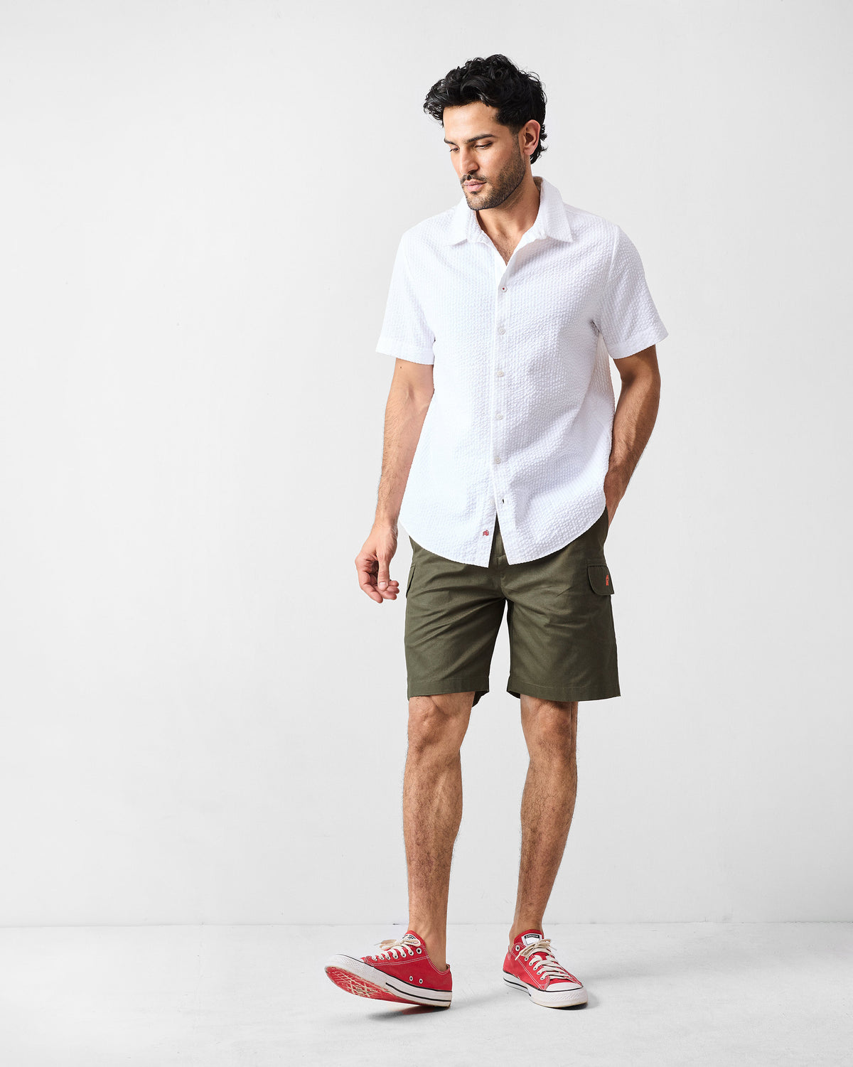 Olive utility shorts worn with a white short-sleeve shirt.