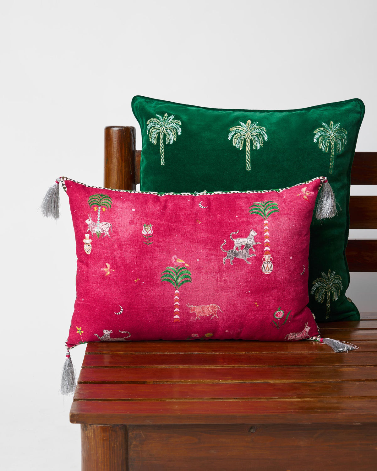 Magenta Harappa cushion cover with folk animals, palms, and grey corner tassels.