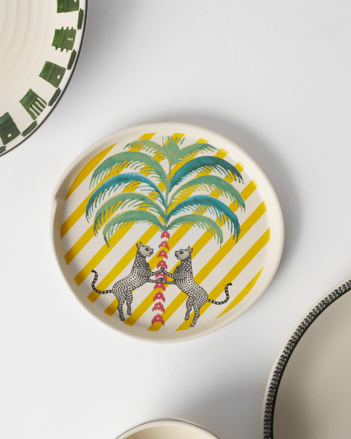 Bagh dessert plate with two leopards flanking a palm on yellow stripes.