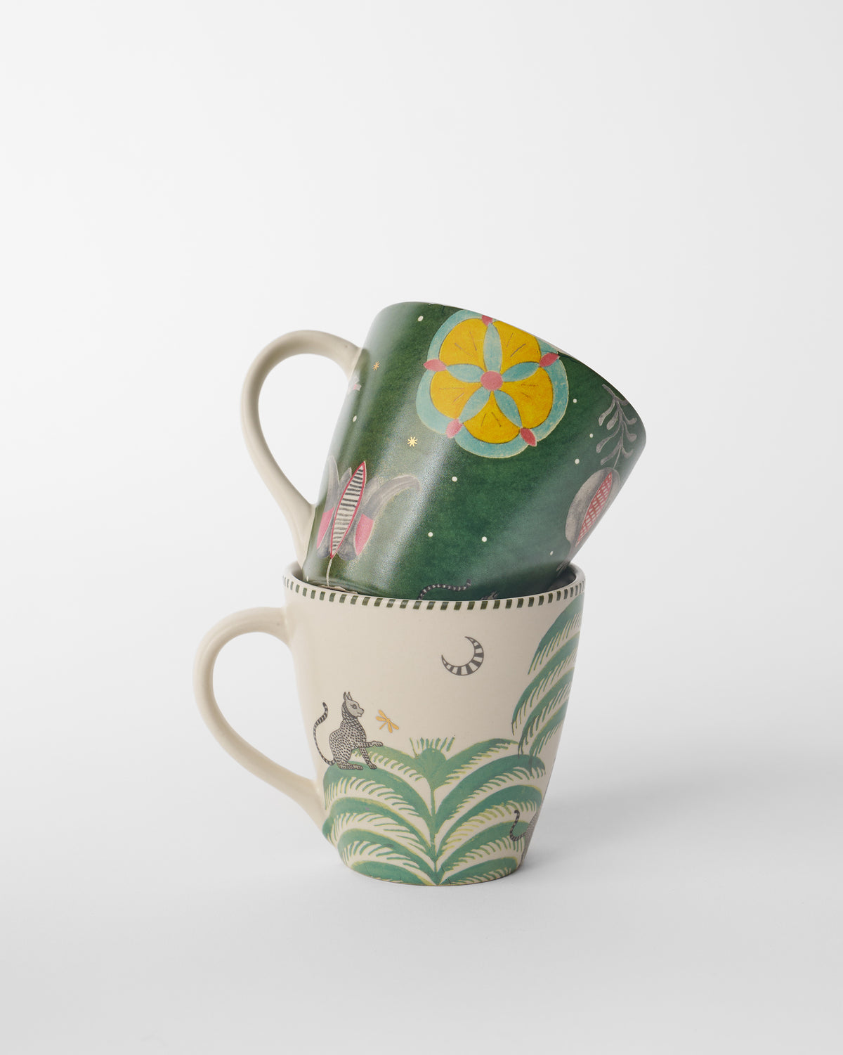 Forest-green Indus mug stacked on a cream mug with a macaque and moon.