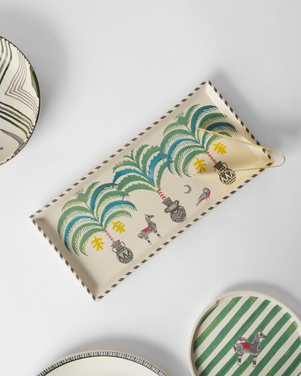 Indus cookie tray with gold tongs shown among coordinating Indus plates.