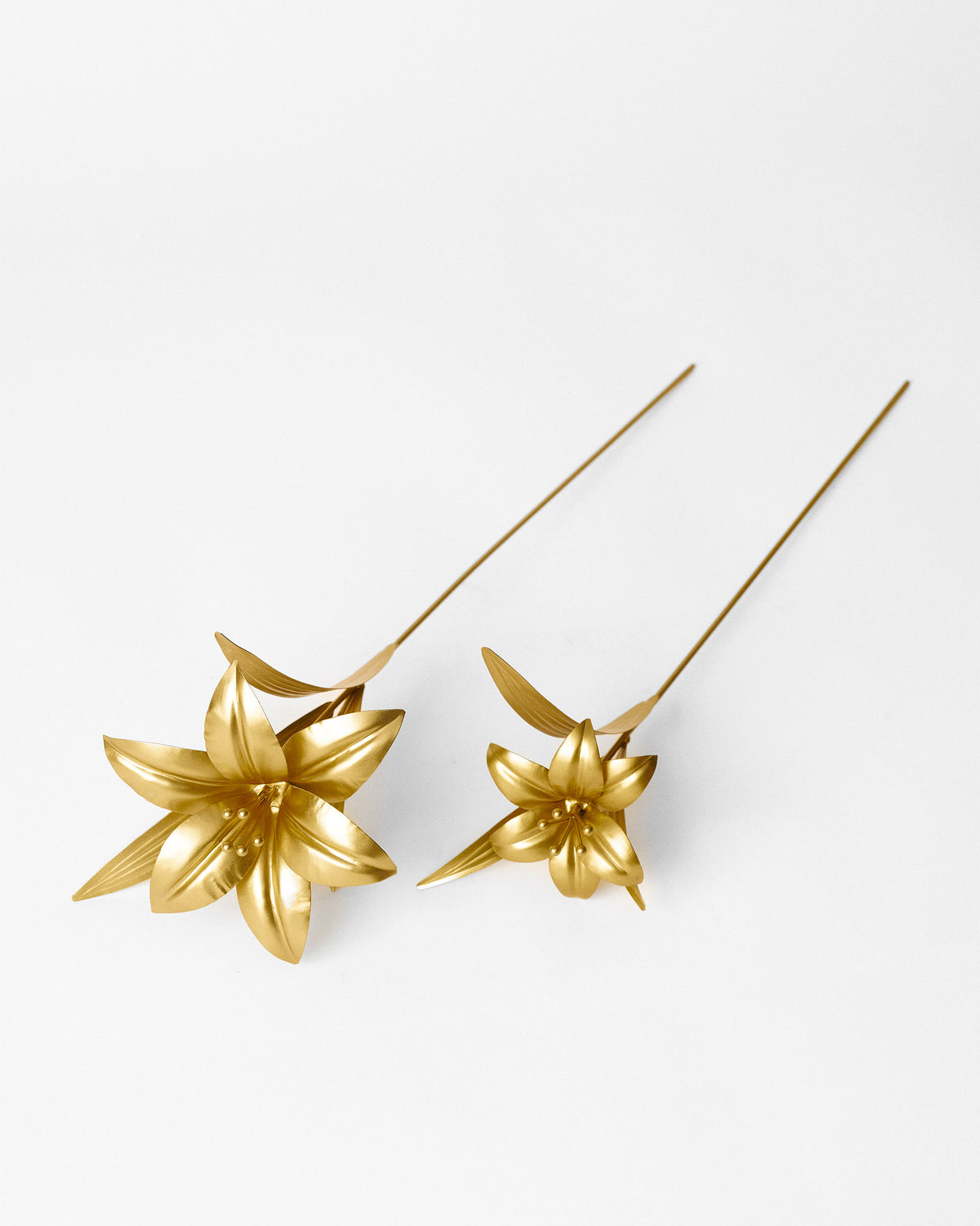 Pair of gold Lily Accent Pieces laid diagonally.