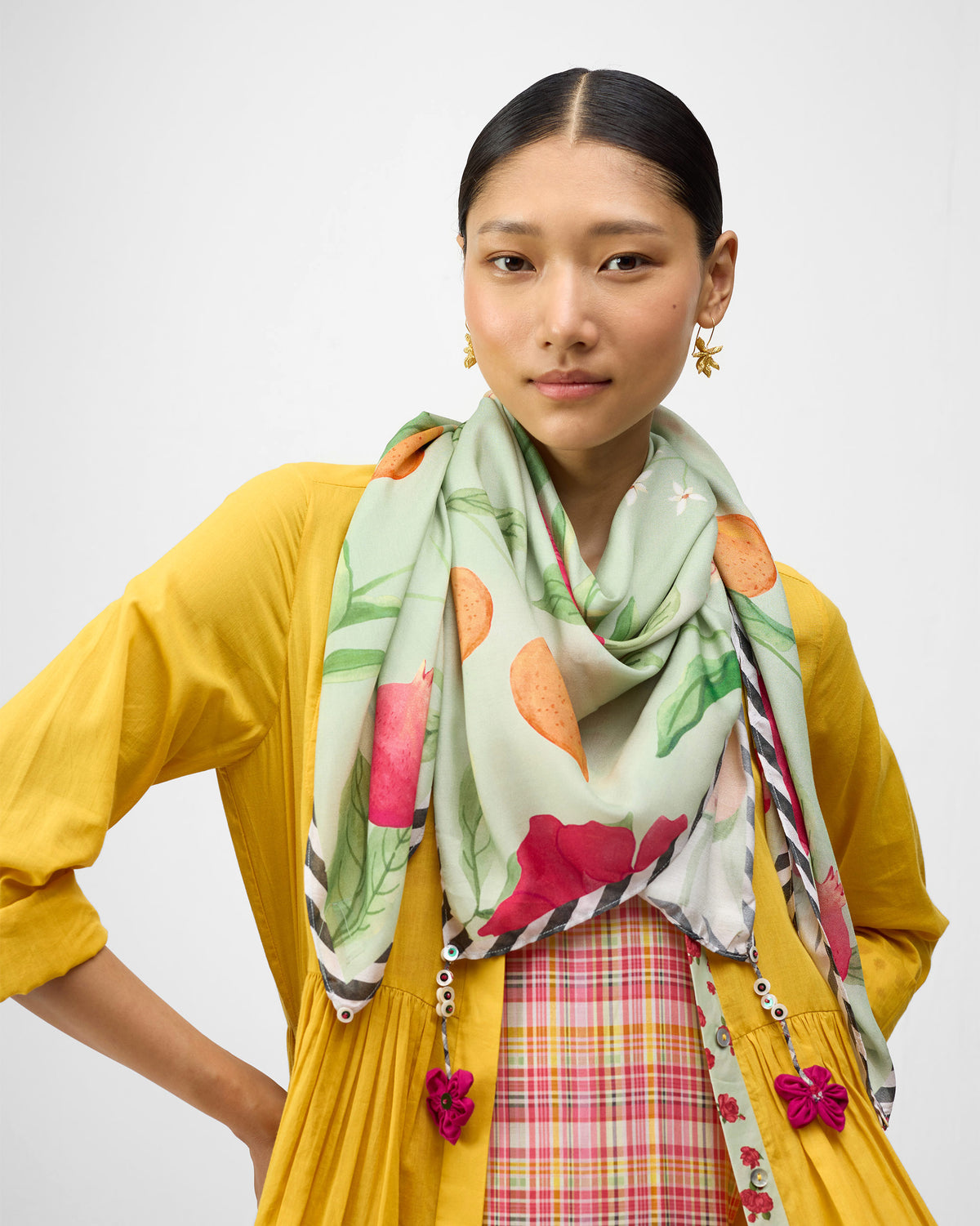 Person wearing a mint Dusk Garden scarf with orange fruit and pink flowers.