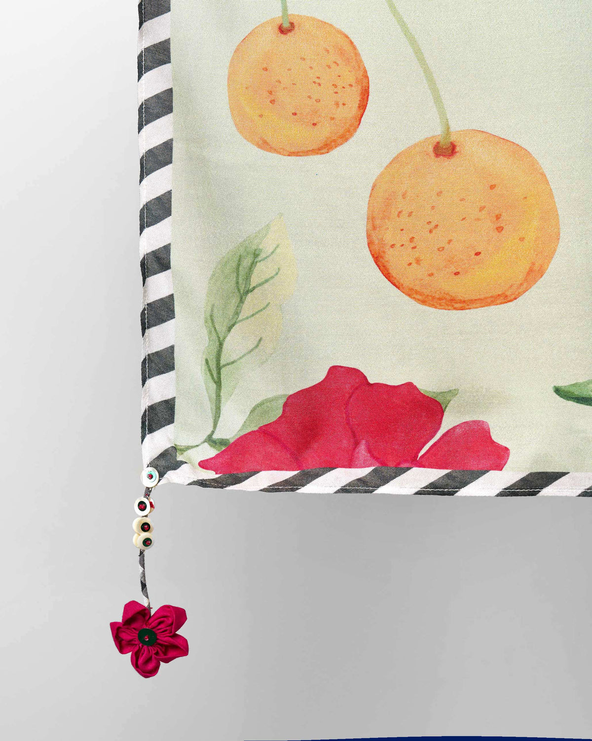 Close-up of a Dusk Garden scarf corner showing orange fruit and a pink flower.