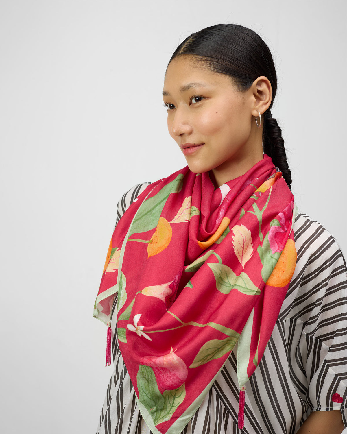 Person wearing a red-pink Dusk Garden scarf with orange fruit.